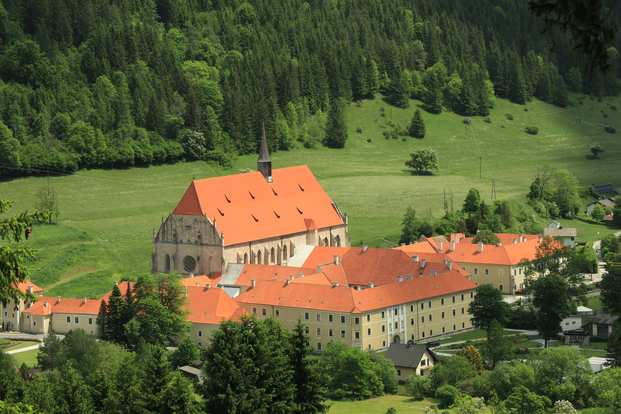 Stift Neuberg mit roten Dächern inmitten der bewaldeten Berge des Mürztals